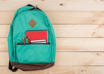 blue backpack, red notebooks and pencils on wooden table