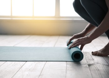 Young woman doing yoga twisting mat indoors near window