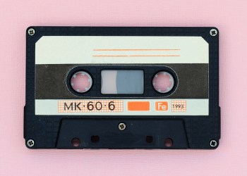 Old audio tape cassette on a pink background. Top view, old technology concept