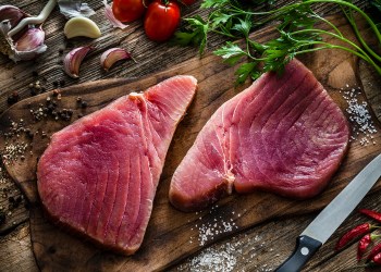 Two raw tuna steaks on rustic wooden table