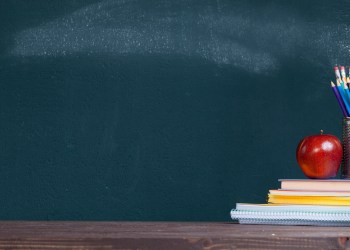 Pencil tray on notebook stack in classroom. Back to school concept