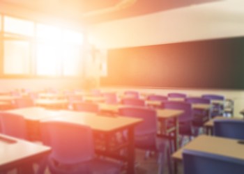 School classroom in blur background without young student; Blurry view of elementary class room no kid or teacher with chairs and tables in campus.