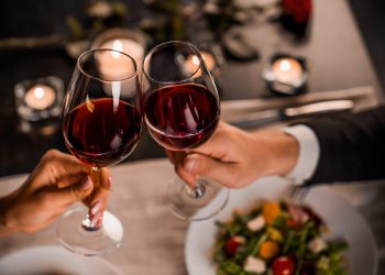 Close up of young couple toasting with glasses of red wine at restaurant