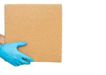 Delivery man holding cardboard boxes / copy space. Delivery by courier in medical rubber gloves. The shipping time during coronavirus