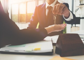 estate agent giving house keys to man and sign agreement in office