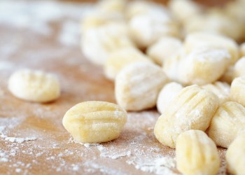 Homemade gnocchi on a flour-covered, wood surface