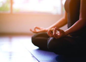 Women in meditation while practicing yoga in a training room. Happy, calm and relaxing.