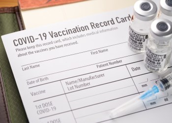 COVID-19 vaccination record card with vials and syringe