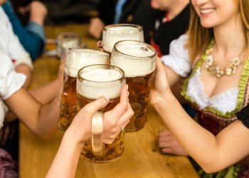 Bavarian girls in traditional Dirndl dresses are drinking beer and having fun at the Oktoberfest in Riverhead