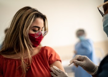 Teenage Latina girl being vaccinated - wearing face mask