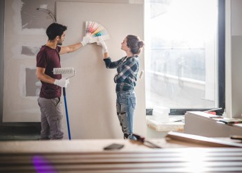 Young couple choosing the right color for their wall while renovating apartment.