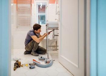 Young man fixing a leak under the bathroom sink