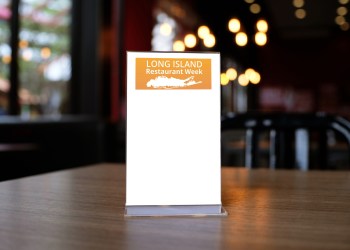 Mock up Menu frame standing on wood table in Bar restaurant cafe. space for text with Long Island Restaurant Week logo Hamptons