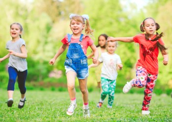 Many different kids, boys and girls running in the park on sunny summer day in casual clothes.