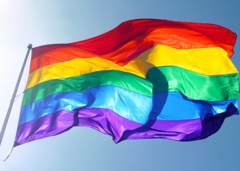 Rainbow flag, sun, wind, and blue sky