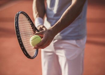 Cropped image of handsome man playing tennis on tennis court outdoors