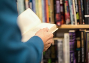 Cropped image of senior male customer holding book