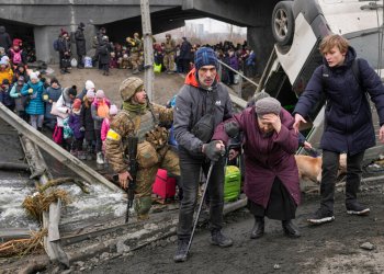 Elderly woman is assisted crossing the Irpin river while fleeing her home in Irpine, Ukraine