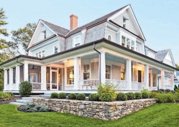 Exterior view of custom-built home with exterior lighting and manicured landscaping.