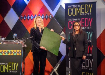 Caroline Hirsch presents Journey Gunderson with an iconic harlequin from her Carolines on Broadway comedy club