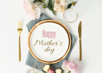 Happy Mother's day concept. Beautiful table setting with golden cutlery and peony flowers, flat lay