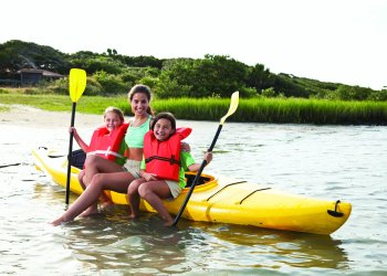 Teenage girl (17 years) with little girls (8-9 years) sitting on kayak in summer camp