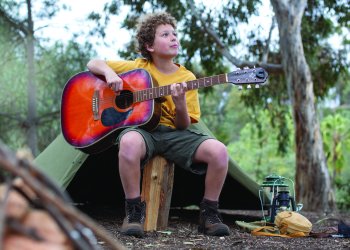 Boy playing guitar at a Jewish summer camp campsite