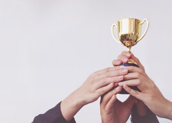 Hand of Team business holding a golden trophy, Concept Teamwork