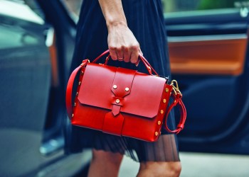 Women is holding a Balenciaga handbag near luxury car