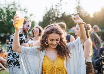 A front view of young woman with drink dancing at summer festival.