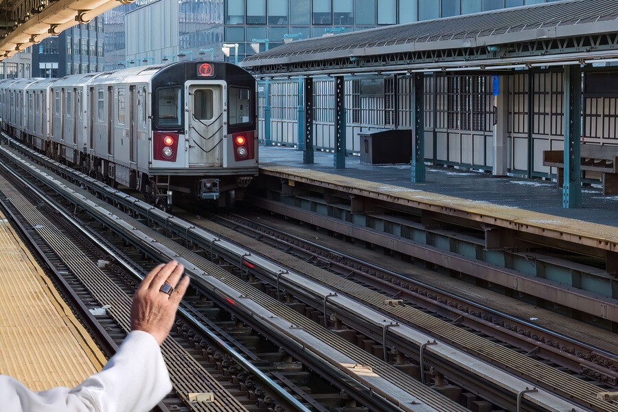 New York subway train arriving at outdoor covered platform among highrises on cold day