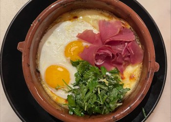 Brunch at Lulu Kitchen includes a Raclette Fonduta for two with two sunny-side-up eggs, prosciutto, Raclette cheese, potato, pickled cucumber, and truffled herb salad.