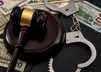 Bail bond system, bailing out of jail and innocent until proven guilty conceptual idea with judge wooden gavel, dollar banknotes and handcuffs check fraud