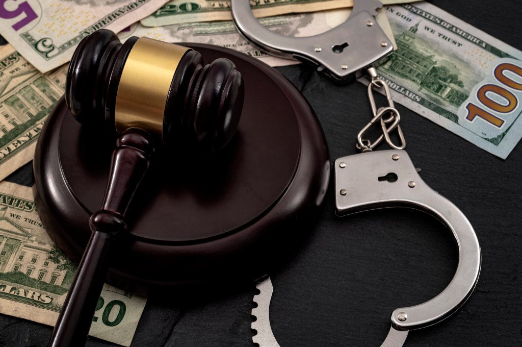 Bail bond system, bailing out of jail and innocent until proven guilty conceptual idea with judge wooden gavel, dollar banknotes and handcuffs check fraud