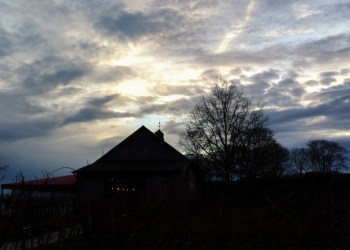 Looking west towards a sunset shining through the clouds at a winery on the North Fork of Long Island.