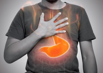 A man burning sensation in chest from acid reflux on gray background.