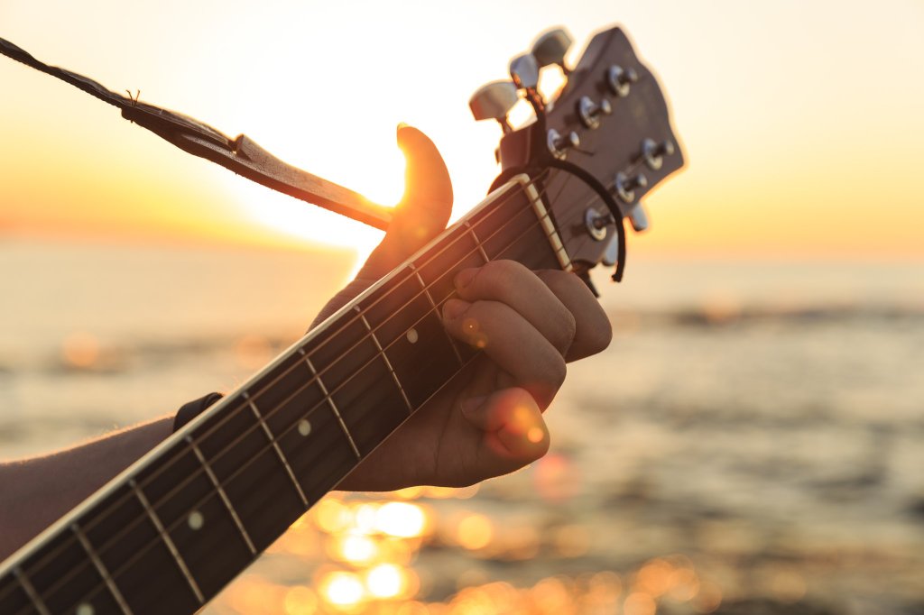 Hand on guitar strings at sunset - There will be sunset music in Sagaponack in the Hamptons on Sept. 21.