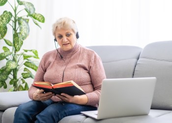 Woman with bible and laptop in front of her connected to online church services durring the covid 19 outbreak