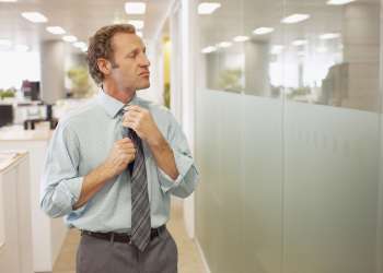 Businessman adjusting tie in office