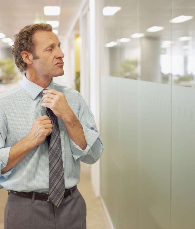 Businessman adjusting tie in office