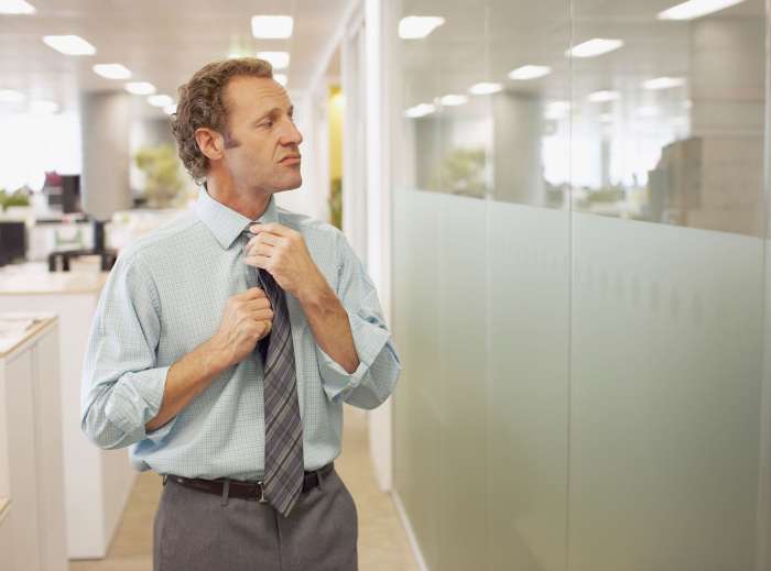 Businessman adjusting tie in office