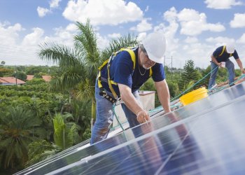 Two men installing solar panel on house roof