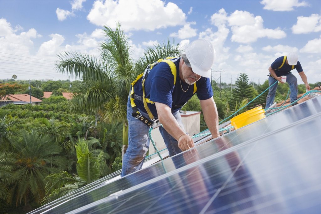 Two men installing solar panel on house roof