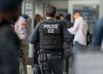 An ICE agent monitors hundreds of asylum seekers being processed upon entering the Jacob K. Javits Federal Building on June 6, 2023 in New York City. Deportation