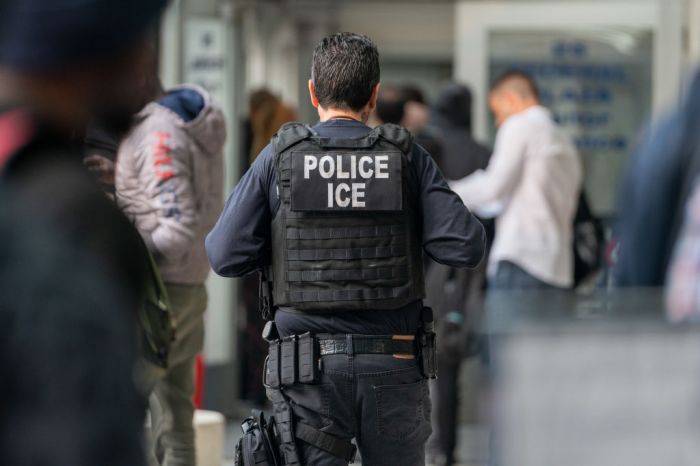 An ICE agent monitors hundreds of asylum seekers being processed upon entering the Jacob K. Javits Federal Building on June 6, 2023 in New York City. Deportation