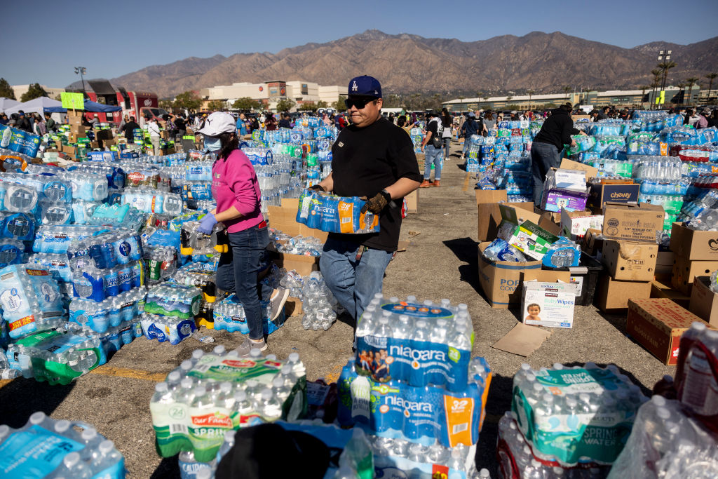 Volunteers carry water for evacuees from the Eaton fire at a donation center in Santa Anita Park, Arcadia, California. Officials warn that strong winds are pushing deadly wildfires through Los Angeles, devastating neighborhoods and displacing thousands.