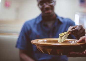 A closeup of a man donating money under the lights with a blurry background - philanthropic giving