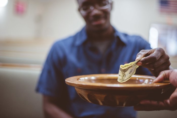 A closeup of a man donating money under the lights with a blurry background - philanthropic giving