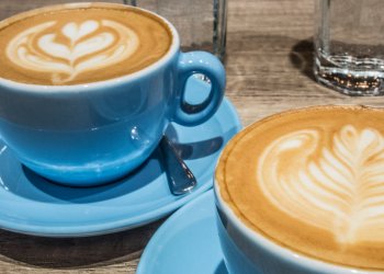 blue cups of coffee with foam designs inside coffee shop